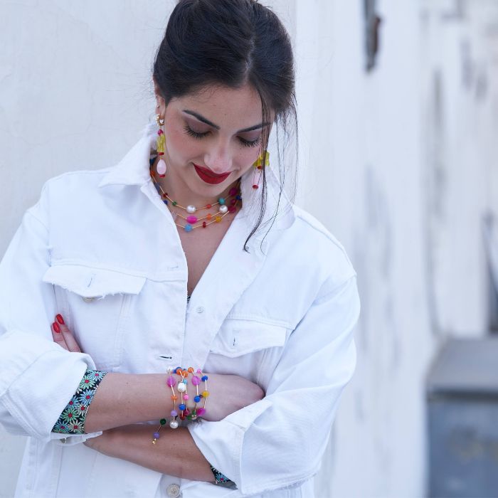 Dalila tutta RAINBOW: indossa una collana da 42cm insieme ad una da 90 girata due volte e 5 bracciali elastici tutti nella versione ORIGINAL