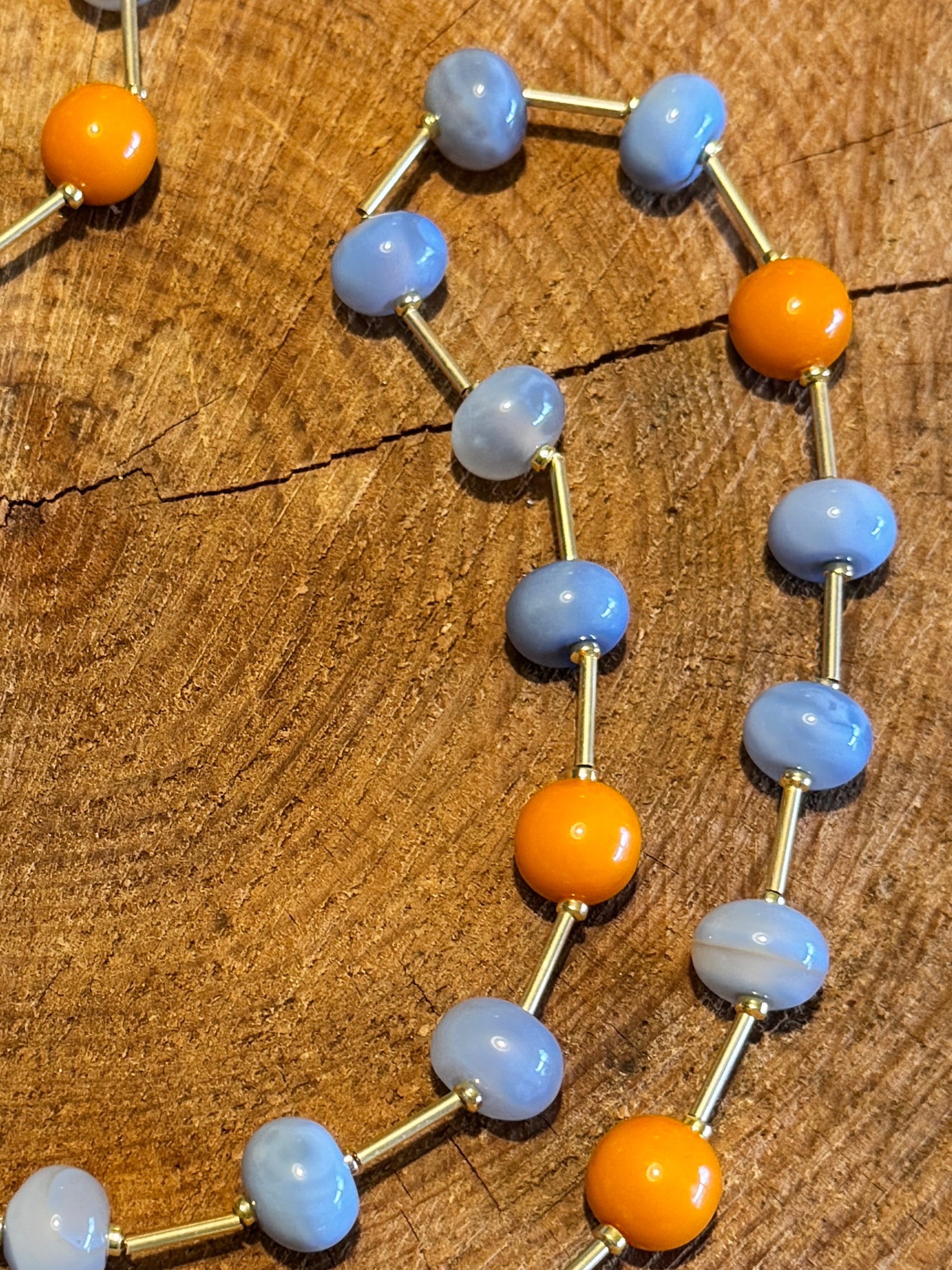 Dettaglio pietre dure naturali agata azzurra, pallini in resina cantalupo, rondelle di ematite oro e astine in ottone dorato.Una collana, mille modi. Zero sforzo.