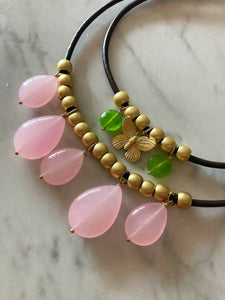 collana in cuoio con elementi in zama dorata e 5 pendoli in quarzo rosa, qui nella foto insieme al collarino di cuoio con farfalla e pietre verdi