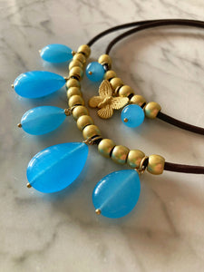 collana in cuoio con rondelle in zama dorata e 5 pendoli in agata blu , nella foto insieme alla collana con farfalla in zama e pallini di agata blu