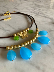 Collana in cuoio con rondelle dorate e pendoli in agata blu, nella foto mostrata insieme alla collana con farfallina in zama e tondini in pietra verde